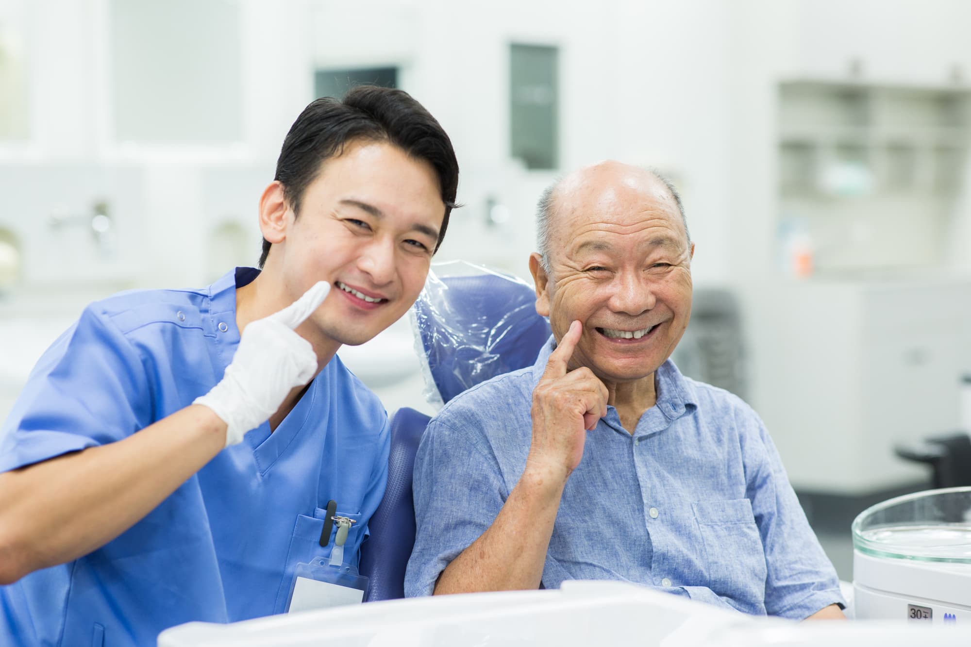 笑顔で歯を指さす歯科医師と老人
