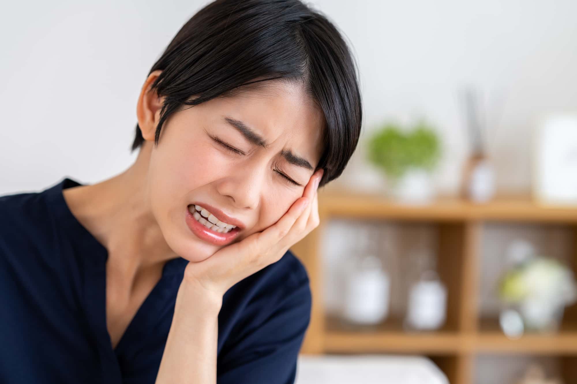 顎関節症で痛む顎をおさえる女性